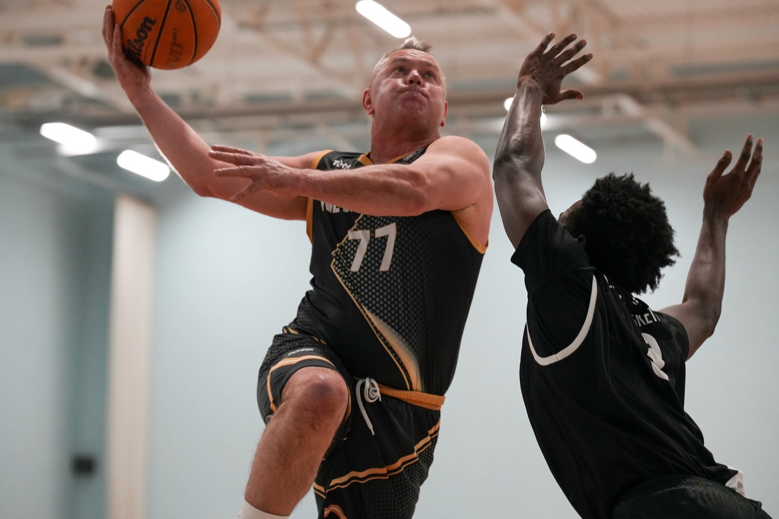 A player driving to the basket and finishing over a defender